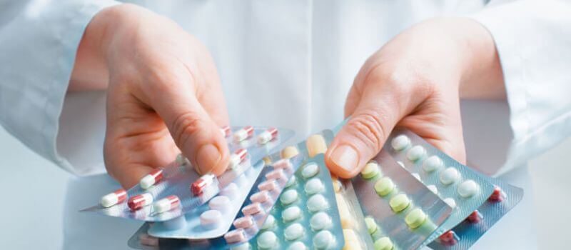 A doctor holding various pills and tablets, representing personalized medicine.